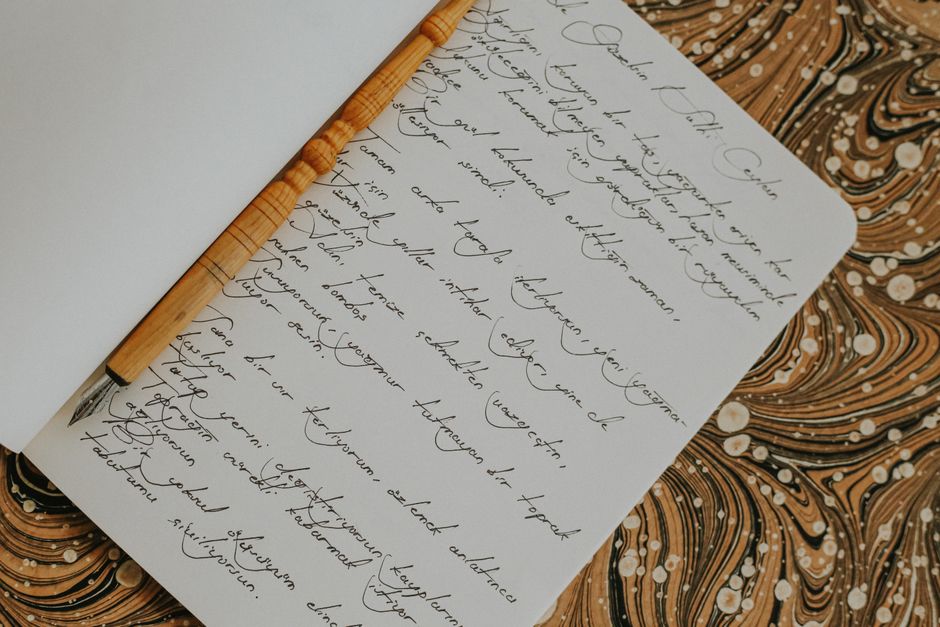 Elegant wooden fountain pen laying on a notebook filled with cursive handwriting.