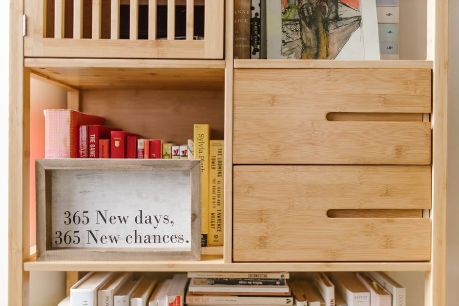 Wooden bookshelf with books and a motivational quote sign: '365 New days, 365 New chances.'